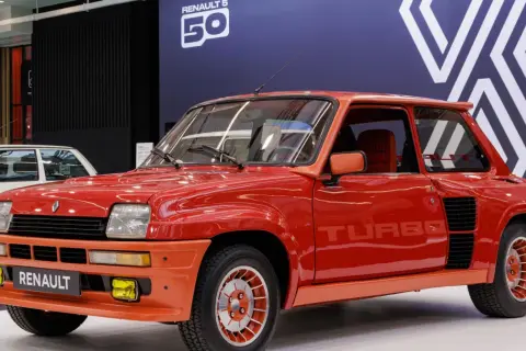 Czerwony Renault 5 Turbo z lat 80. błyszczy na wystawie. Charakterystyczne logo "TURBO" na drzwiach i pomarańczowe akcenty podkreślają jego sportowy charakter.