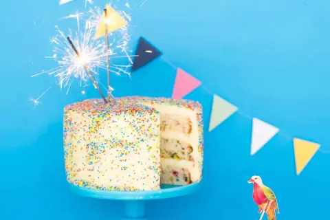 En festlig funfetti tårta med stjärnljus och en färgglad fågeldekoration. Perfekt för ett kalas!