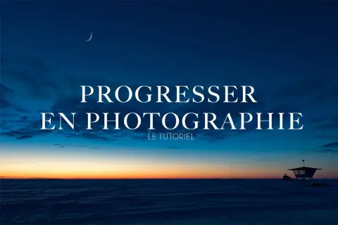 Un ciel crépusculaire bleu profond avec une lune fine au-dessus du texte "Progresser en photographie". Un paysage enneigé et une cabine de sauveteur au loin.