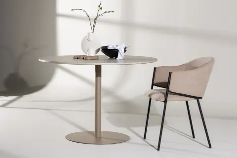Runt matbord inspiration med en modern stol. En vas med kvistar och skålar på bordet.