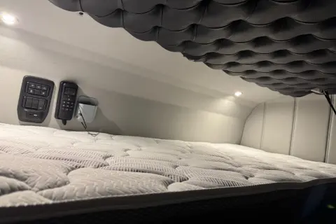 Confortable couchette camion americain avec matelas moelleux et commandes à portée de main.