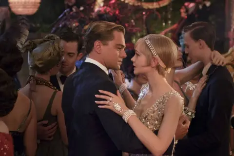 Para Gatsby'ego, taniec z Daisy to chwila magii. Ona w błyszczącej sukni, on w eleganckim garniturze, otoczeni gośćmi na przyjęciu.