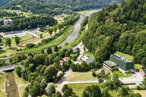 Malowniczy widok na Muszynę z rzeką i lasami. W oddali widać kompleks budynków, w tym sanatorium Revita.