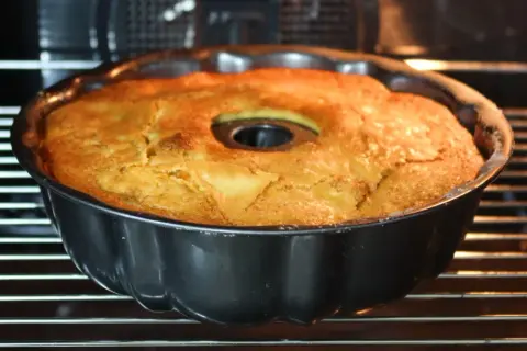 Bizcocho de manzana y naranja recién horneado en su molde, con un dorado perfecto. ¡Huele delicioso!