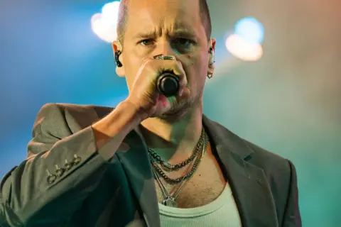 Krzysztof Zalewski śpiewa "Annuszka", w szarym garniturze i z łańcuchami na szyi.