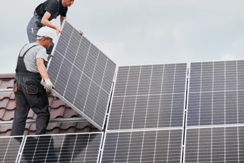 Instaladores colocan placas solares en un tejado, asegurando el anclaje para la energía limpia.