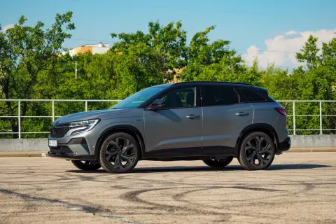 Szary Renault Austral na tle zieleni. Wiele osób szuka **Renault Austral opinie** przed zakupem.