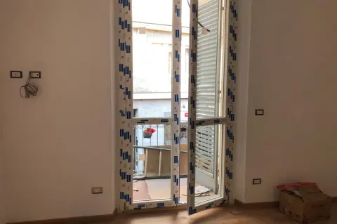 Nuova **doppia finestra per isolamento termico** installata in un ambiente in fase di ristrutturazione. Si intravede un cortile esterno.