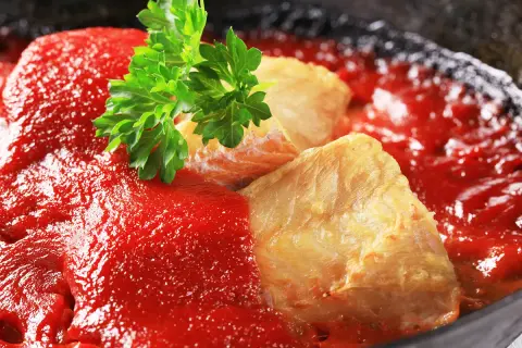 Délicieuse lotte recette en sauce tomate, garnie de persil frais. Un plat savoureux prêt à être dégusté.