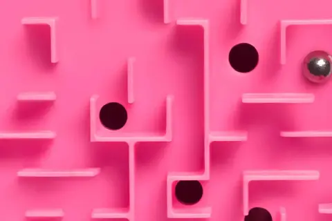 Un labyrinthe rose avec des trous noirs et une bille argentée, évoquant le multi-threading dans la résolution de problèmes complexes.