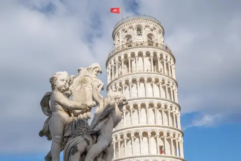 Die Torre de Pisa, ein schiefer Turm, ragt hinter einer barocken Skulptur auf.