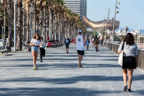Spacer po promenadzie w Barcelonie, gdzie panuje przyjemna hiszpania temperatura roczna. Ludzie jeżdżą na deskorolkach i rowerach, ciesząc się słońcem.