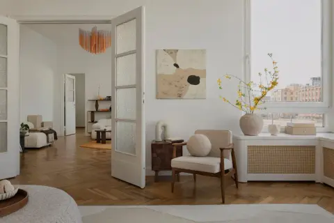 Un soggiorno in stile **organic modern** con mobili chiari, parquet a spina di pesce e un quadro astratto.