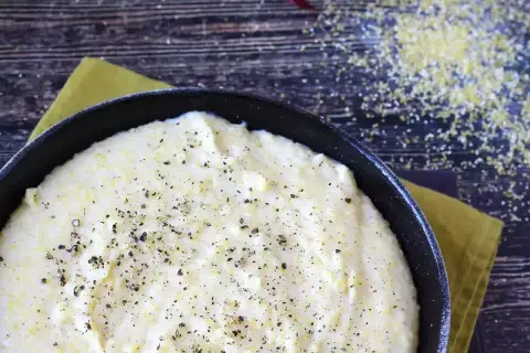 Pyszna, kremowa polenta z mąki kukurydzianej, doprawiona świeżo mielonym pieprzem, gotowa do podania.