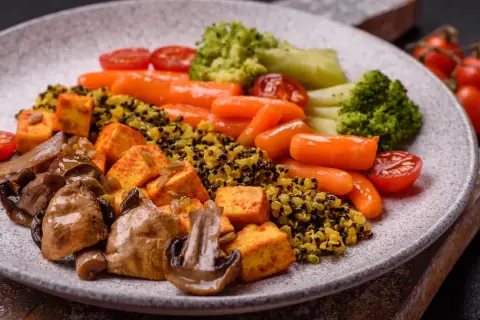 Gesundes Abendessen zum Abnehmen: Quinoa mit Tofu, Pilzen, Karotten, Brokkoli und Tomaten.