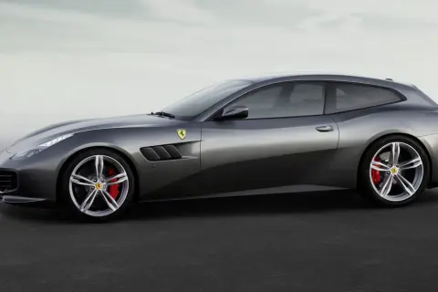 Szary Ferrari FF, sportowe kombi z charakterystycznymi wlotami powietrza i czerwonymi zaciskami hamulcowymi, prezentuje się na tle mglistego nieba.