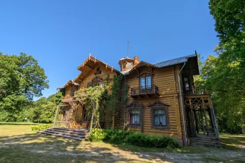 Drewniany dworek z werandą i balkonami, otoczony zielenią. Piękna leżajsk trasa widokowa.