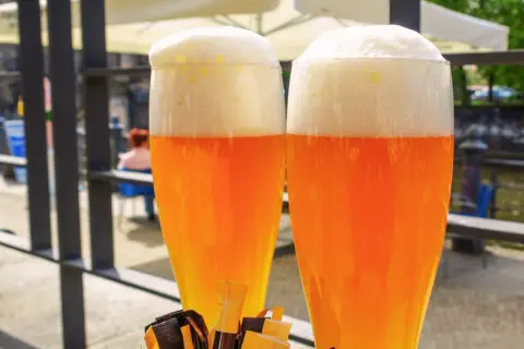 Due bicchieri di hefeweizen birra dorata con schiuma bianca e soffice, pronti per essere gustati all'aperto.