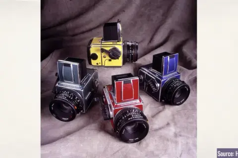 A collection of vintage Hasselblad 500c cameras in various colors: yellow, green, red, and blue.