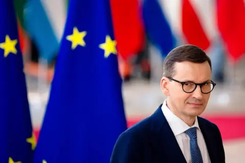 Mateusz Morawiecki w okularach, na tle flag UE. Czy to moment, kiedy Morawiecki podpisał zielony ład?