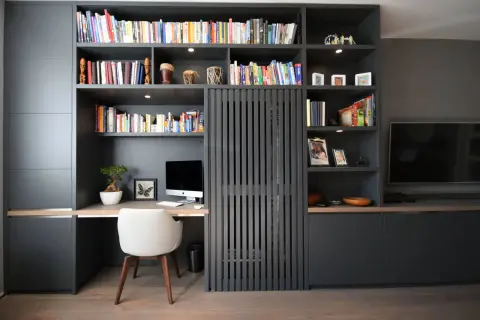 Gemütliche arbeitsecke im wohnzimmer mit Schreibtisch, Computer und Bücherregal.