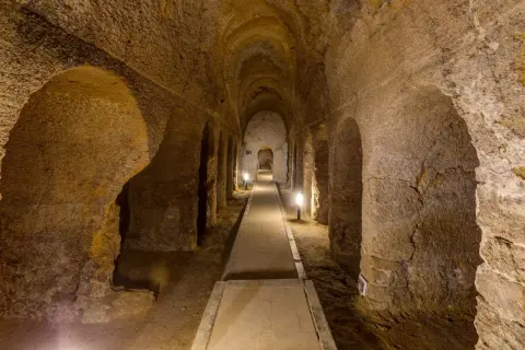 Corridoio sotterraneo scavato nella roccia a Camerano, Ancona, con illuminazione soffusa che crea un'atmosfera suggestiva.