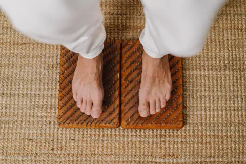 Voeten staan op spijkermat, een oefening voor balans en ontspanning.