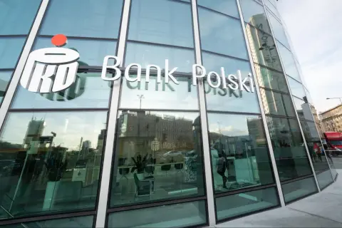 Logo PKO Bank Polski na szklanej fasadzie. W środku wnętrze banku, gdzie można założyć pko bp lokaty.