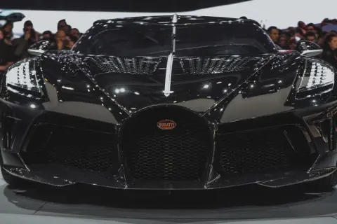 Czarny Bugatti, najdroższe auto na świecie, błyszczy na wystawie, przyciągając wzrok tłumu.