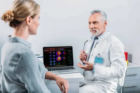 Arzt erklärt Patientin die Ergebnisse einer Mibi-Szintigraphie und bespricht mögliche Risiken.