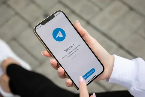 Dłoń trzyma smartfon z otwartą aplikacją Telegram. To szybka i bezpieczna apka do wysyłania wiadomości.