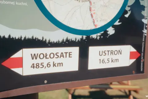 Tablica informacyjna na głównym szlaku bieszczadzkim. Wskazuje odległości do Wołosate (485,6 km) i Ustronia (16,5 km).