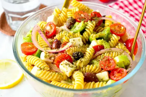 En härlig grekisk pastasallad med fusilli, körsbärstomater, fetaost, oliver och rödlök. Perfekt för en lätt lunch eller middag.