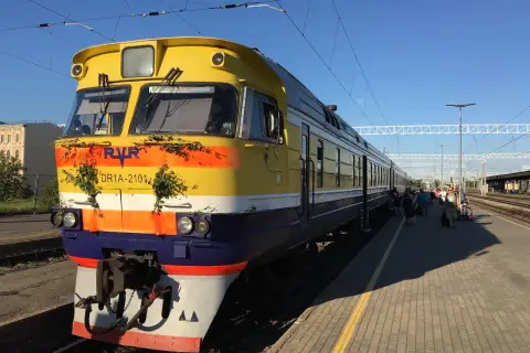 Gelber Zug mit grüner Deko am Bahnhof, bereit für die Fahrt von Riga nach Tallinn.