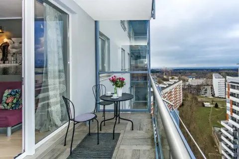 Balkon z widokiem na Gdańsk Przymorze. Stolik z kawą i kwiatami czeka na gości.