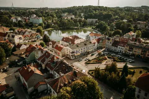 Urokliwe Mrągowo z lotu ptaka. Jezioro, kolorowe kamienice i zielone dachy tworzą malowniczy krajobraz. Odkryj mrągowo atrakcje!