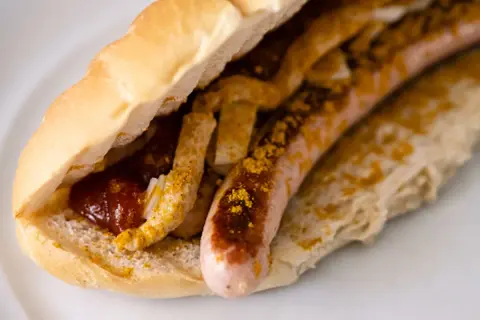 Ein Brötchen mit Wurst, Ketchup und Currypulver, wie bei einem bosna rezept.