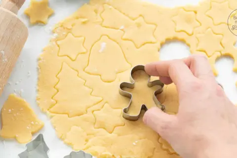 Mit diesem Kekse Rezept entstehen Sterne, Tannenbäume und Lebkuchenmännchen. Ein Holz-Nudelholz liegt daneben.