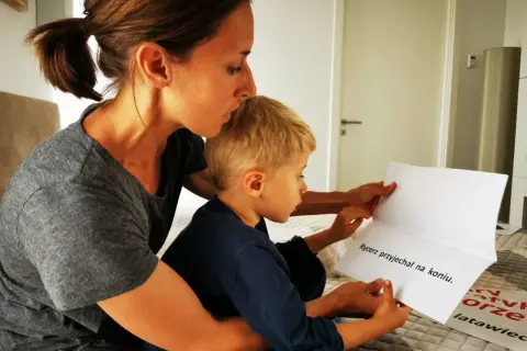 Mama czyta synkowi, kiedy czytać dziecku to ważny moment. Na kartce napisano "Rycerz przyjechał na koniu".