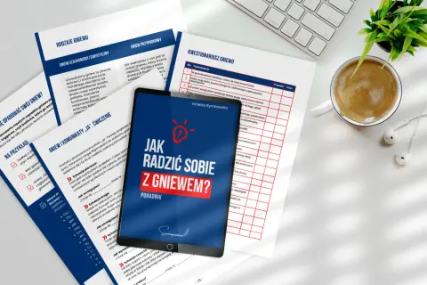 Jak radzić sobie z gniewem? Poradnik na tablecie, obok kubek kawy i słuchawki.
