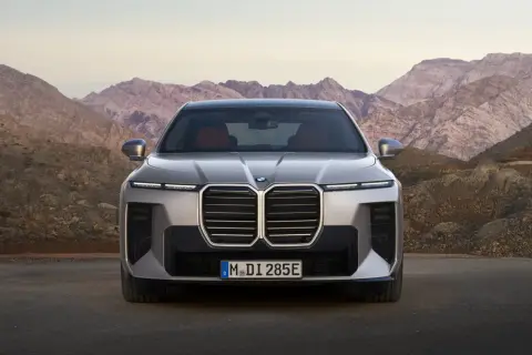 Nowe BMW Serii 7, z imponującym grillem i nowoczesnymi światłami, prezentuje się na tle górskich krajobrazów. Sprawdź jego BMW 7 cenę.