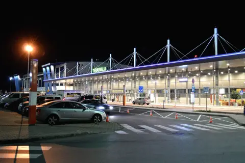 Dojazd z dworca PKP do Katowice-Pyrzowice. Terminal A lotniska nocą, zaparkowane samochody i autobus.