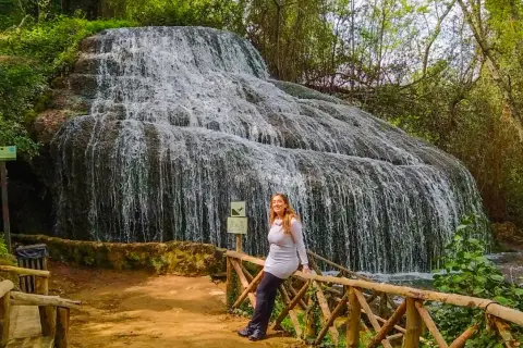 Cascada espectacular, ideal para descubrir qué ver cerca de Calatayud. Una mujer sonríe apoyada en una barandilla de madera.