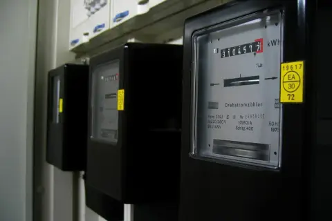 Trzy liczniki energii elektrycznej, każdy pokazujący inną jednostkę energii. Jeden z nich wskazuje 3104572 kWh.