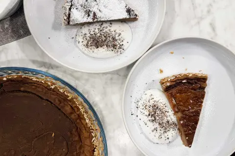 Två tallrikar med glutenfria havrekakor med kardemumma och grädde. En hel kaka i en glasform.