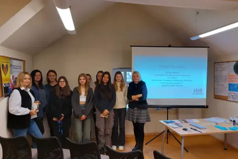 Grupa osób na tle ekranu projekcyjnego w Miejskim Ośrodku Pomocy Społecznej w Lublińcu.