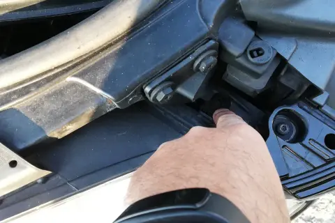 Palec wskazuje śrubę mocującą reflektor podczas wymiany żarówki audi a4 b7 przód prawa.