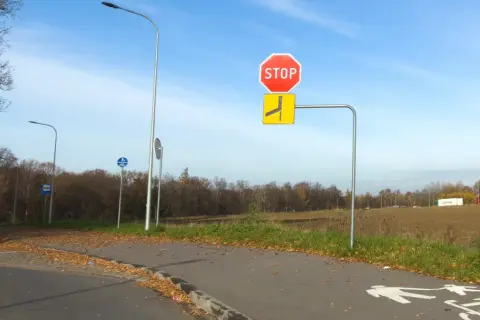 Znak STOP i znak informujący o drodze z pierwszeństwem łamanym. Na ścieżce rowerowej namalowane symbole pieszych i rowerzystów.