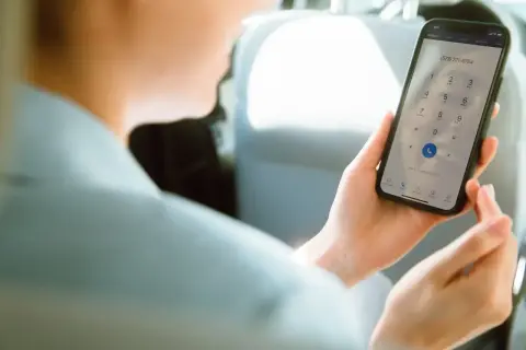 Osoba w samochodzie wybiera numer na telefonie, pokazując, jak działa voip.