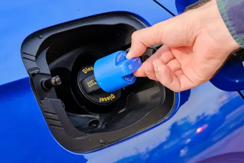 Dłoń zamyka niebieską nakrętkę z napisem AdBlue. To płyn do redukcji emisji spalin w dieslach.